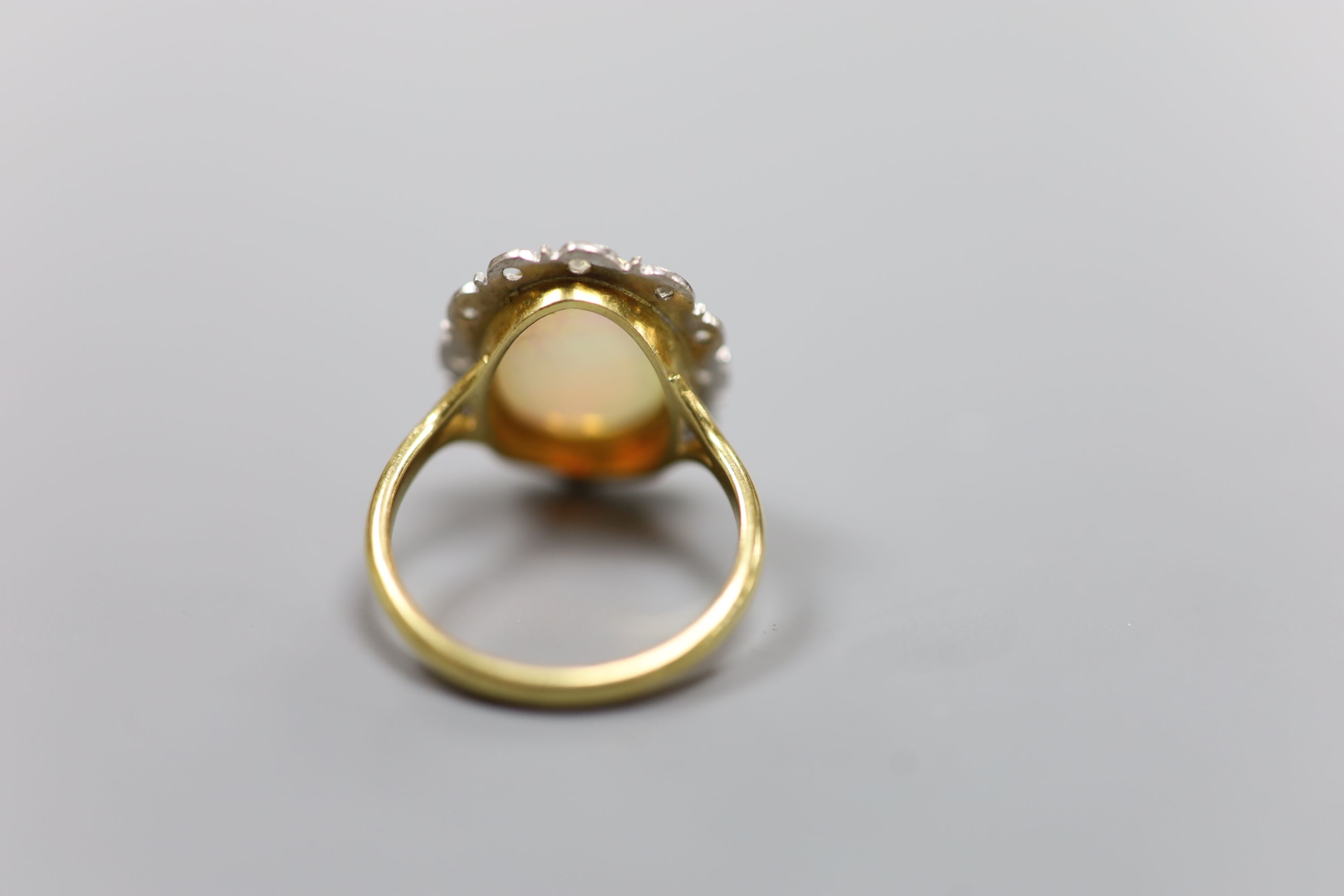 An 18ct, white opal and illusion set diamond oval cluster ring (one diamond missing)